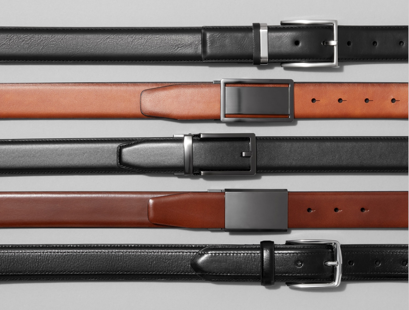 Five men's leather belts on a grey background