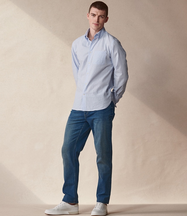 Man in a light blue shirt and jeans with white sneakers