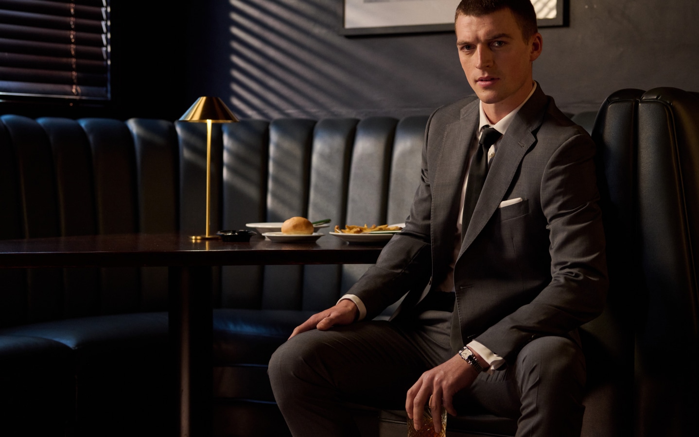 Man in a charcoal suit seated in a restaurant