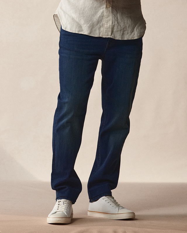 Man in dark jeans and white sneakers. Pants and shorts up to 40% off.