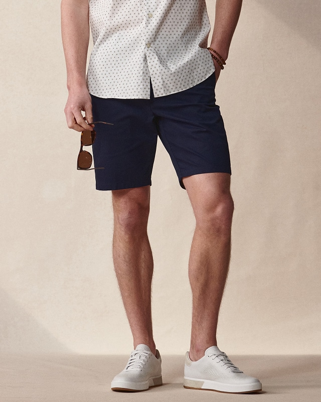 Man in navy shorts and a printed shirt. Pants and shorts buy 1 get 1 50 percent off.