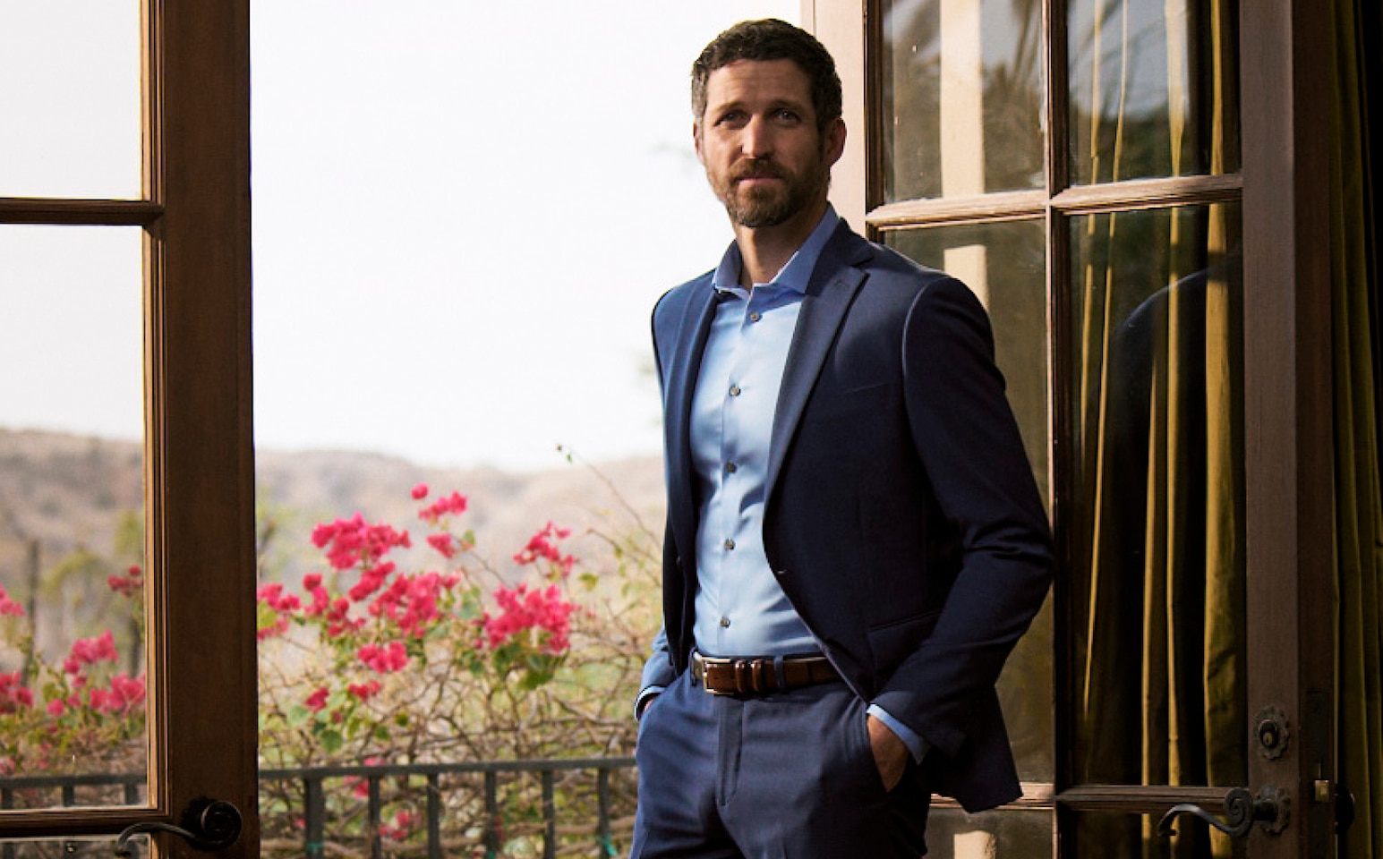 Man wearing a custom blue suit standing near a doorway