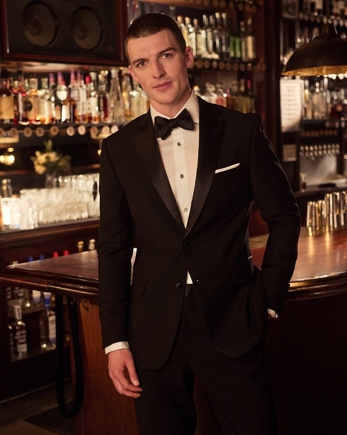 Man in a black tuxedo at a bar