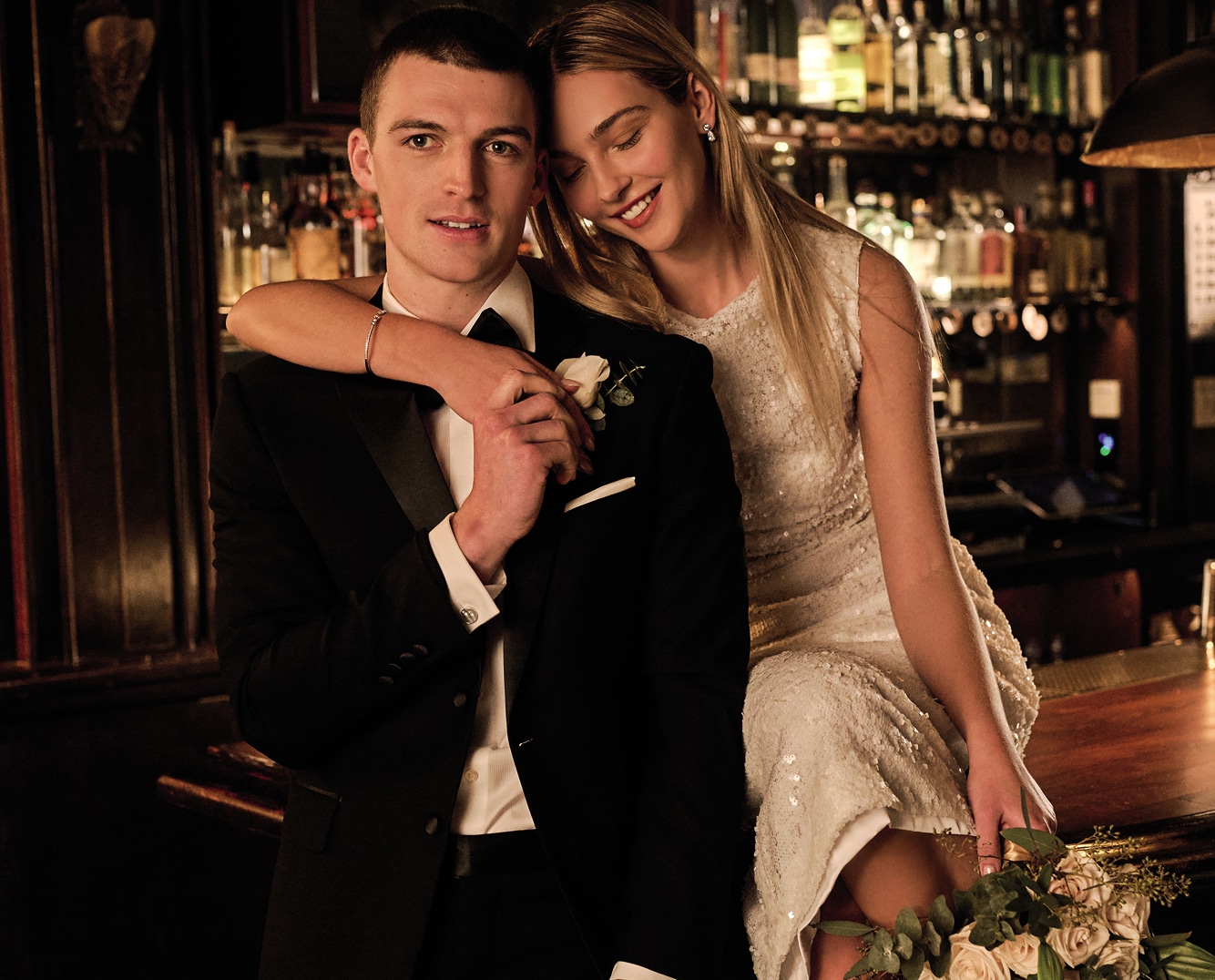 Couple in formalwear at a bar. Man in a black tuxedo.