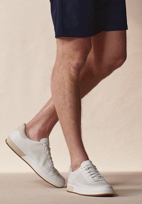 Man in navy shorts wearing white leather sneakers.