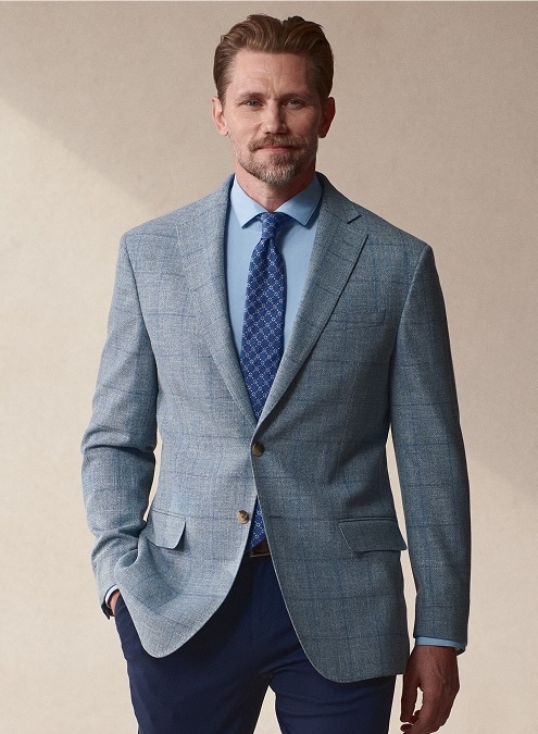 Man in a light blue checked sport coat, blue dress shirt and patterned tie.