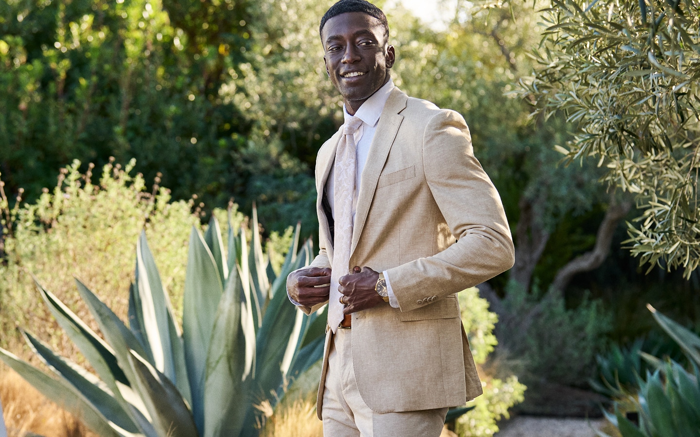 Man wearing a tan suit outdoors.