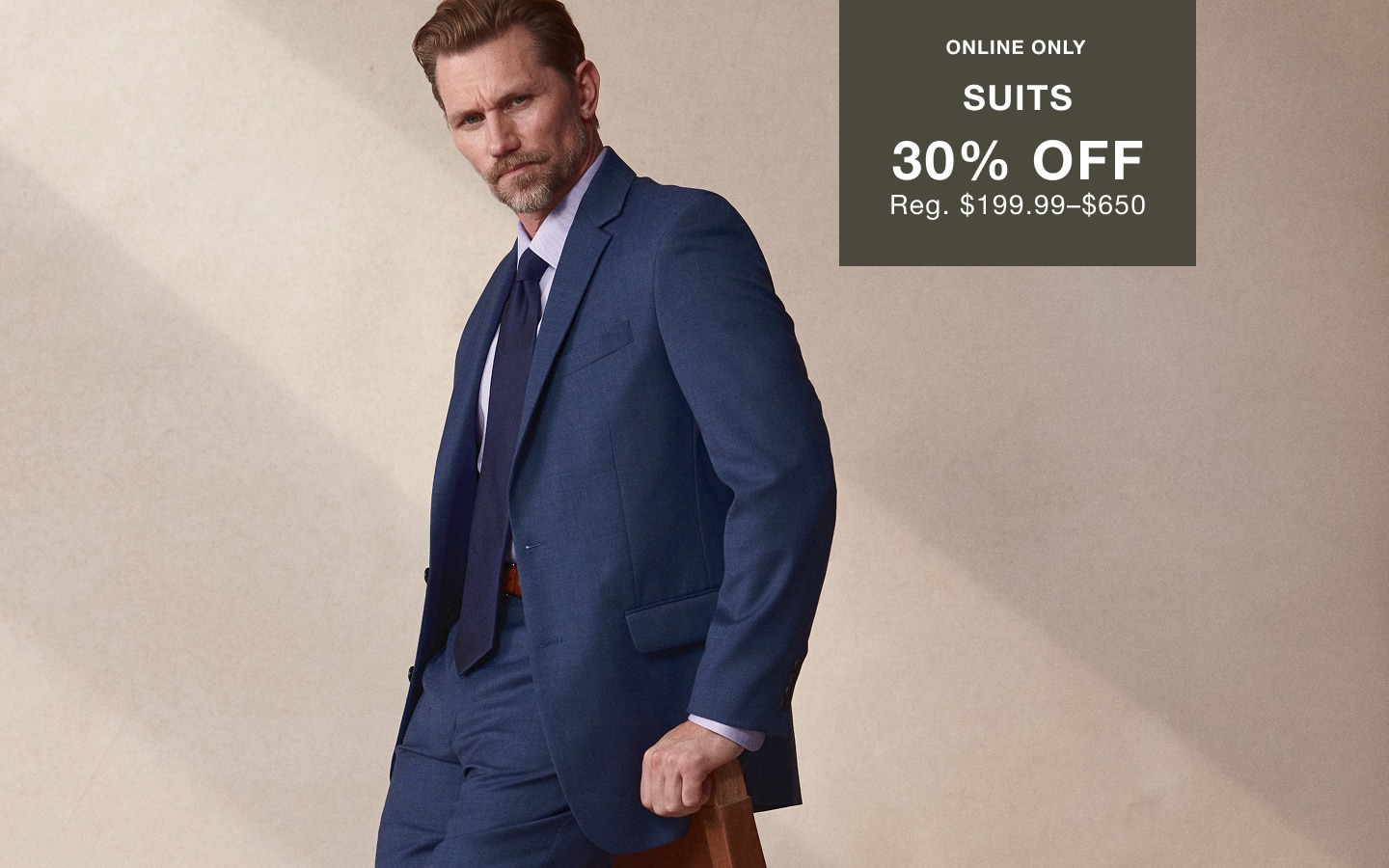 Man wearing a navy suit. Online only. Suits 30% off. Regular price $99.99 to $650.