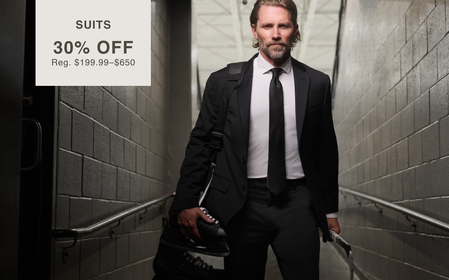 Man wearing a navy suit. Online only. Suits 30% off. Regular price $199.99 to $650.00.