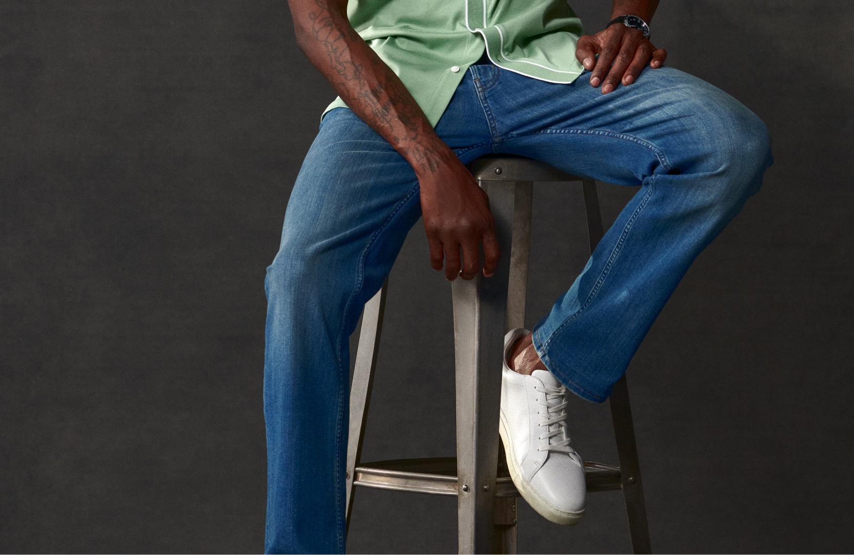 Golfer in gray golf shorts, belt, patterned polo, and white glove resting a club