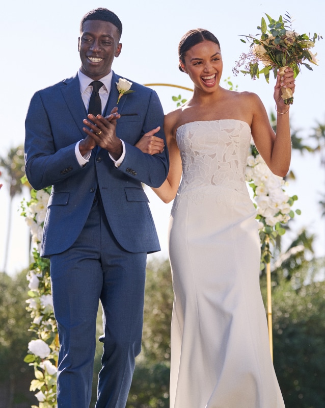 Pronto Uomo Platinum suits. Couple in wedding attire outdoors.