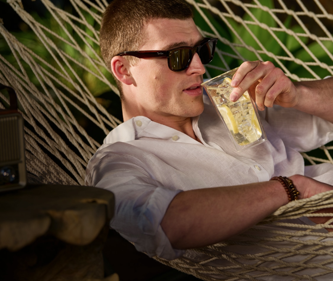 Man relaxing in a hammock wearing a white linen shirt