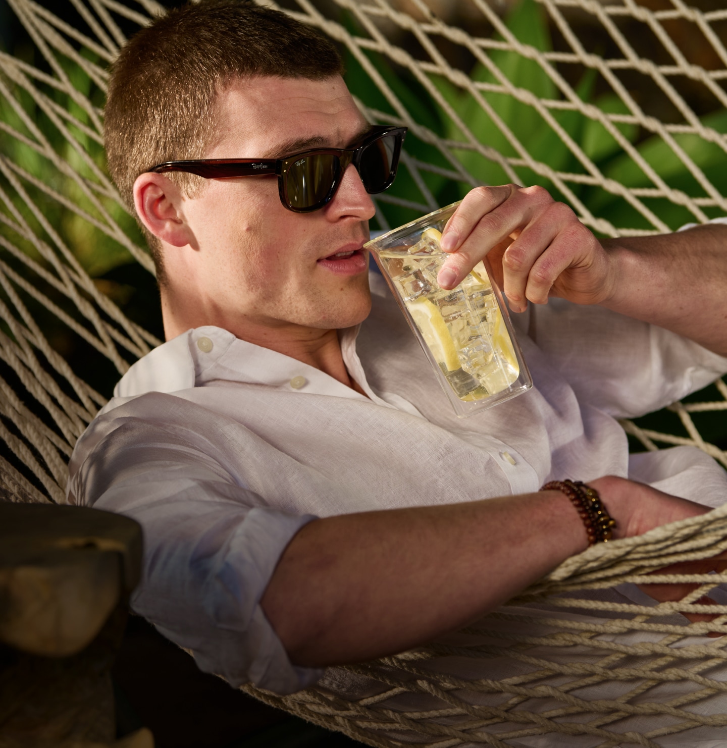 Man relaxing in a hammock wearing a white linen shirt